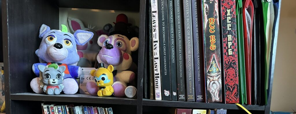 ScreamingWyvern's Bookshelf showcasing Dunegon Crawl Classics and FNAF stuffies